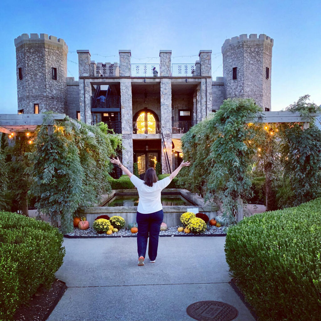 Angela Brooks standing with arms wide open in front of Kentucky Castle showing how to save money on travel with MWR Life membership